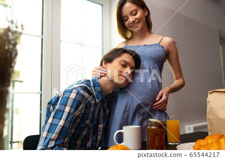 Caring man embracing pregnant woman during breakfast Caring man embracing pregnant woman during breakfast 65544217