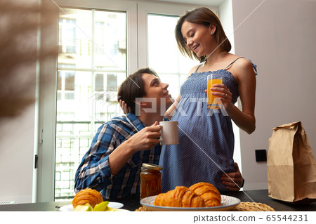 Merry young man enjoying meals with pregnant woman Merry young man enjoying meals with pregnant woman 65544231