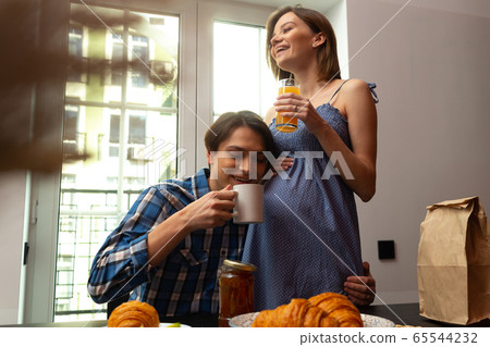 Happy future parents enjoying drinks in cozy kitchen Happy future parents enjoying drinks in cozy kitchen 65544232