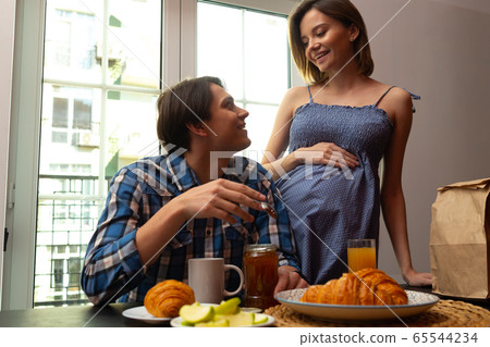 Happy pregnant woman preparing meals for husband Happy pregnant woman preparing meals for husband 65544234