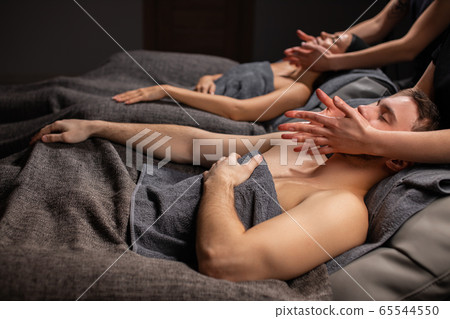 married couple in spa salon getting facial massage 65544550