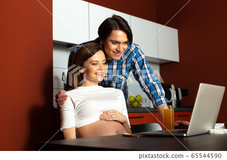 Happy future parents using notebook at home 65544590