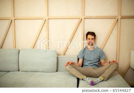 Male with closed eyes sitting in living room Male with closed eyes sitting in living room 65544827