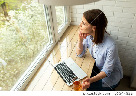 Young woman looking at window at home Young woman looking at window at home 65544832