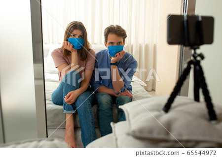 Man and woman in blue masks making shot by mobile phone 65544972