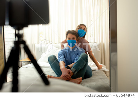 Male and female in blue masks making shot by phone Male and female in blue masks making shot by phone 65544974