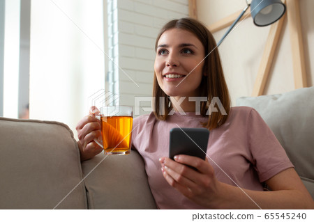 Happy young lady resting with hot drink 65545240