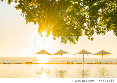 Beautiful tropical outdoor beach sea ocean with umbrella and chiar around outdoor swimming pool at sunset or sunrise time Beautiful tropical outdoor beach sea ocean with umbrella and chiar around outdoor swimming pool at sunset or sunrise time 65545511