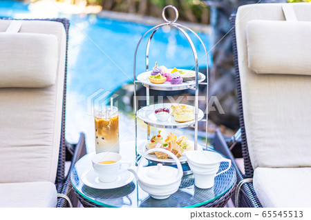 Afternoon tea set with latte coffee and hot tea on table neary chair around swimming pool Afternoon tea set with latte coffee and hot tea on table neary chair around swimming pool 65545513