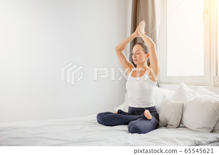 calm yogi woman sit on bed with crossed legs calm yogi woman sit on bed with crossed legs 65545621