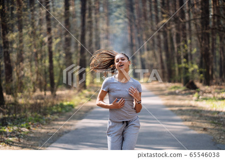 Beautiful young woman running in green park on sunny summer day 65546038