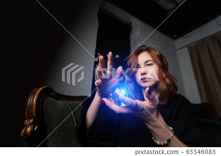 Woman in black suit holding crystal ball 65546083