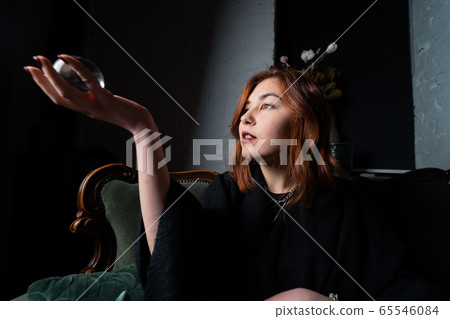 Woman in black suit holding crystal ball 65546084