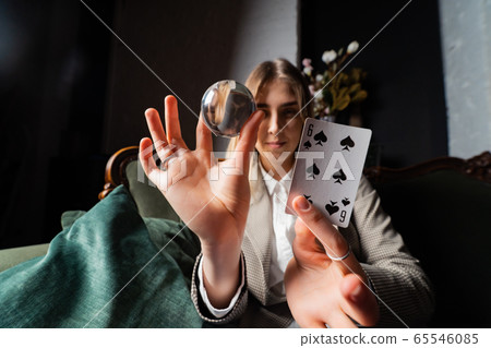 Woman in business suit holding crystal ball and six spade 65546085