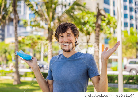 Quarantine is over concept. Man taking off mask against the background of small town houses. We are Quarantine is over concept. Man taking off mask against the background of small town houses. We are 65551144
