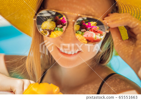 Young woman relaxing and eating fruit plate by the hotel pool. Exotic summer diet. Photo of legs Young woman relaxing and eating fruit plate by the hotel pool. Exotic summer diet. Photo of legs 65551663