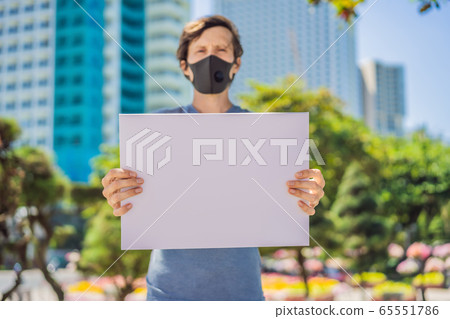 Man in medical mask prevents coronavirus disease holds a poster for free inscriptions. COPY SPACE 65551786