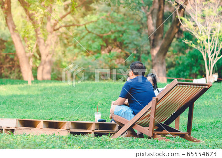 Happiness couple on a summer holiday sitting on garden chairs to relax in the public park. Happiness couple on a summer holiday sitting on garden chairs to relax in the public park. 65554673
