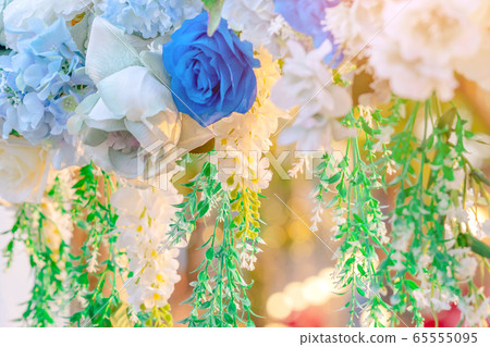 Artificial blue and white flowers decorate the arch as the backdrop in the wedding ceremony. Flowers background. Selective focus. 65555095