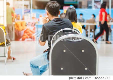 Back view of people order food and wait to take home inside of department store closed due to the coronavirus (Covid-19), Restaurants set chairs for social distancing to waiting for the food. 65555248
