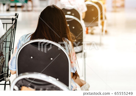 Back view of people order food and wait to take home inside of department store closed due to the coronavirus (Covid-19), Restaurants set chairs for social distancing to waiting for the food. 65555249