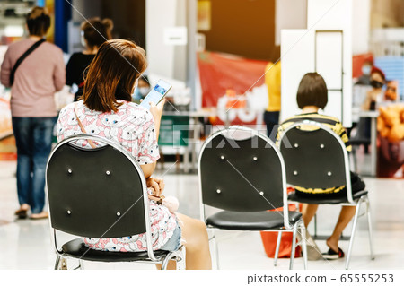 Back view of people order food and wait to take home inside of department store closed due to the coronavirus (Covid-19), Restaurants set chairs for social distancing to waiting for the food. 65555253
