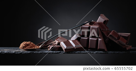 Broken chocolate pieces and cocoa powder on black Broken chocolate pieces and cocoa powder on black 65555702