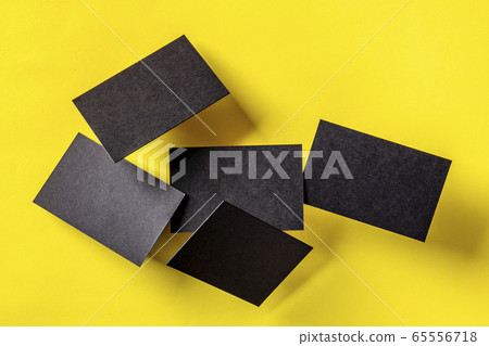 Thick black business cards, floating on a yellow paper background, a mockup for a creative design presentation 65556718