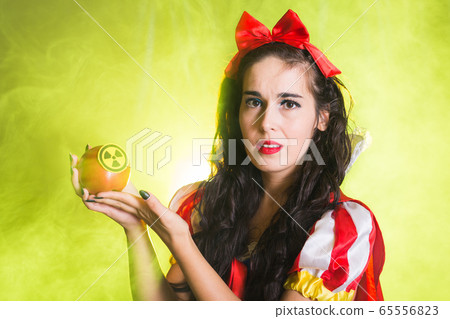 Danger, nuclear and radiation measurement - Girl holds apple with radiation hazard symbol. 65556823