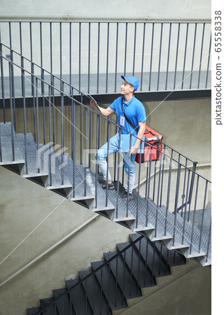 Delivery man walking up the stairs 65558338