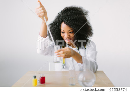 Young beautiful African American girl female with glass equipment in the lab Researcher researching in the laboratory Young beautiful African American girl female with glass equipment in the lab Researcher researching in the laboratory 65558774
