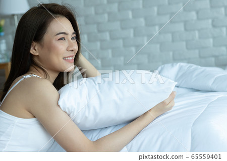 Asian woman cheerful and healthy and wearing white pajamas wake up on bed in bedroom in the morning.at home in holiday. 65559401