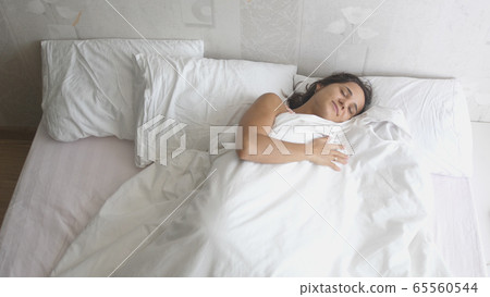 Calm young woman sleeping in comfortable cozy fresh bed enjoying healthy good sleep nap 65560544