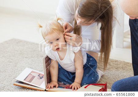 Hearing aid in baby girl's ear. Toddler child wearing a hearing aid at home. Disabled child, disability and deafness concept. Hearing aid in baby girl's ear. Toddler child wearing a hearing aid at home. Disabled child, disability and deafness concept. 65561800