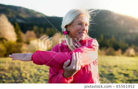 Attractive senior woman doing exercise outdoors in nature, stretching. 65561952