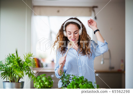 Young woman with headphones relaxing indoors at home. 65562298