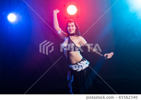 Young woman belly dancer in exotic dress with gold, dancing tribal fusion dance in studio. 65562340