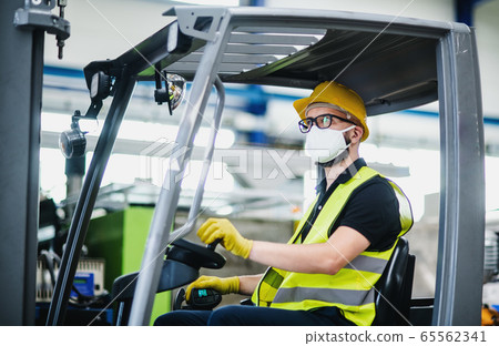 Man worker forklift driver with protective mask working in industrial factory or warehouse. 65562341