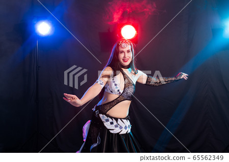 Young woman belly dancer in exotic dress with gold, dancing tribal fusion dance in studio. 65562349
