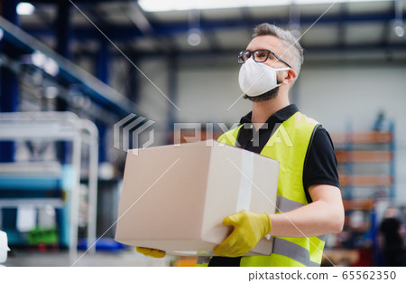Man worker with protective mask working in industrial factory or warehouse. 65562350