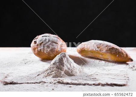 Fresh bread on table close-up in flour placer. Fresh bread on the kitchen table. The healthy eating and traditional bakery concept. Rustic style Fresh bread on table close-up in flour placer. Fresh bread on the kitchen table. The healthy eating and traditional bakery concept. Rustic style 65562472
