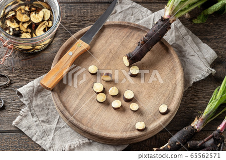 Cutting up fresh comfrey root to prepare tincture Cutting up fresh comfrey root to prepare tincture 65562571