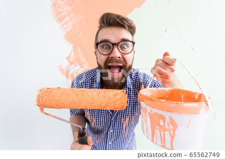 Funny man painting interior wall of home. Renovation, repair and redecoration concept. 65562749
