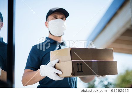 Courier with face mask delivering parcel, corona virus and quarantine concept. 65562925