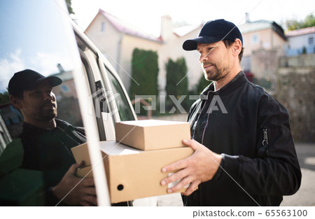 Side view of delivery man courier delivering parcel box in town. Side view of delivery man courier delivering parcel box in town. 65563100