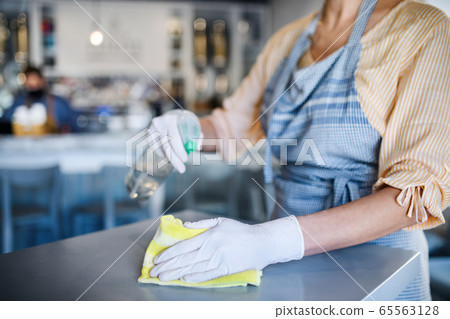Unrecognizable woman working with gloves in coffee shop, disinfecting tables. 65563128