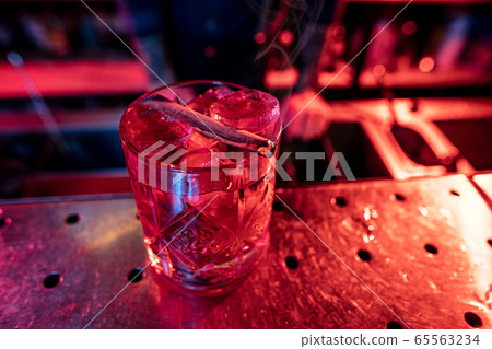 Close up of alcoholic cocktail, beverage, drink, glass full of ice in multicolored neon light 65563234