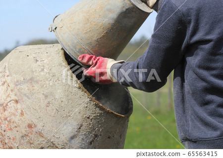 Construction worker mixing ingredients in the concrete mixer at building site Construction worker mixing ingredients in the concrete mixer at building site 65563415