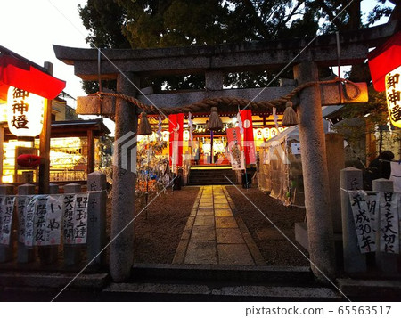黃昏時分,神社的鳥居就在眼前,神燈在左右。正殿前掛著令人印象深刻的紅色橫幅的神社 黃昏時分,神社的鳥居就在眼前,神燈在左右。正殿前掛著令人印象深刻的紅色橫幅的神社 65563517