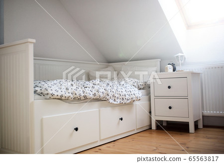 White wooden single bed wnd bedside table in bedroom at home. 65563817